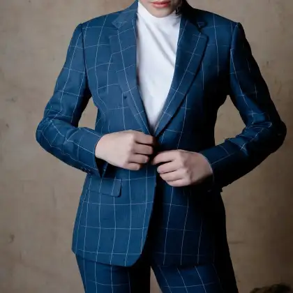 A blue windowpane check suit being buttoned, worn over a white roll neck