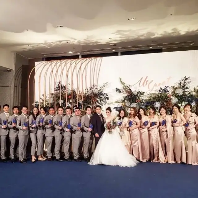 A bride with her bridesmaids and the groom’s party lined up outdoors