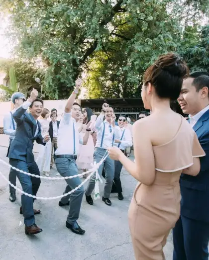 A bride in a champagne dress greeting guests holding a ribbon