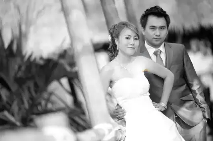 A bride and groom photographed in black and white, the groom in a dark suit
