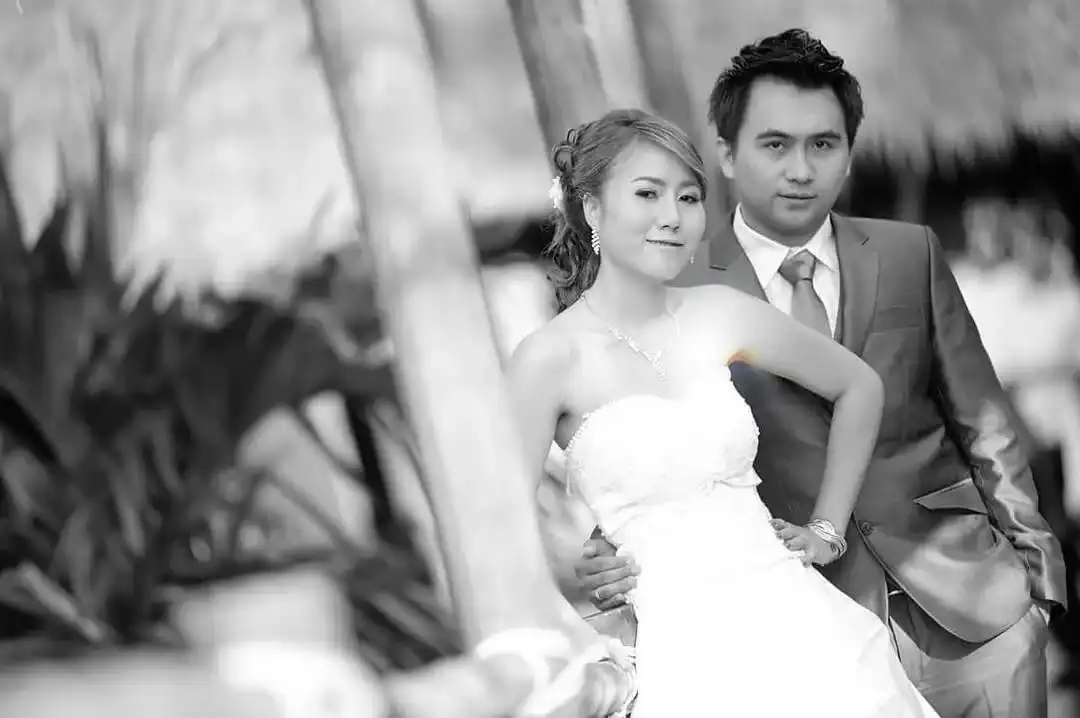 A bride and groom photographed in black and white, the groom in a dark suit