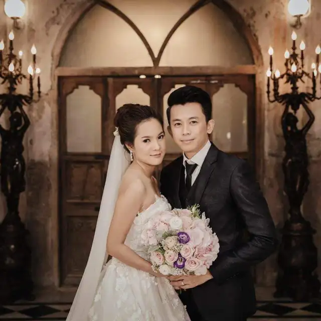 A bride and groom in a chapel doorway, the groom in a dark suit