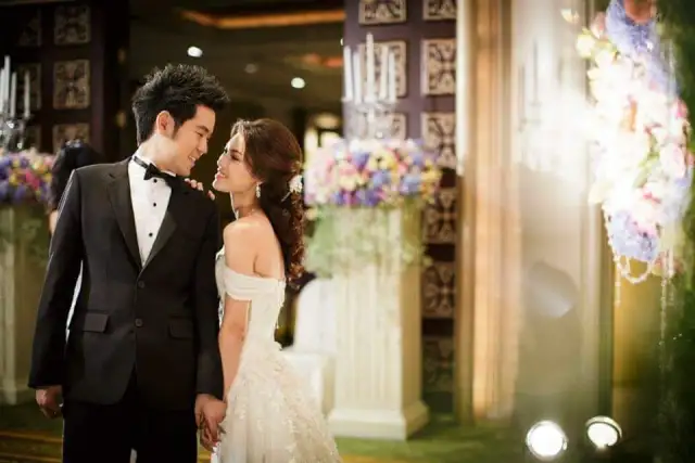A bride and groom face to face, the groom in a black tuxedo