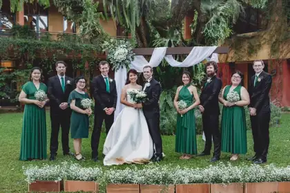 A bride and groom with their party, bridesmaids in green, in a garden