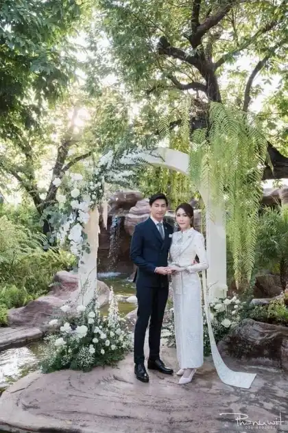 A bride and groom standing together in a garden setting