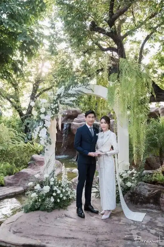 A bride and groom standing together in a garden setting