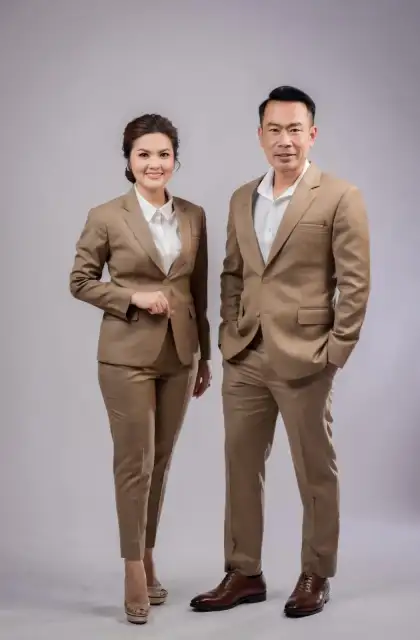 A couple standing together in matching tan suits