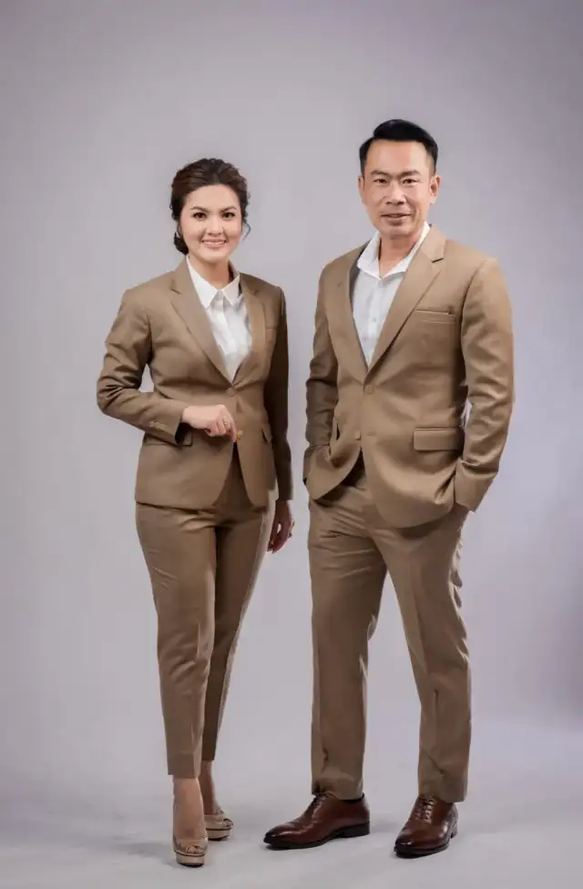 A couple standing together in matching tan suits
