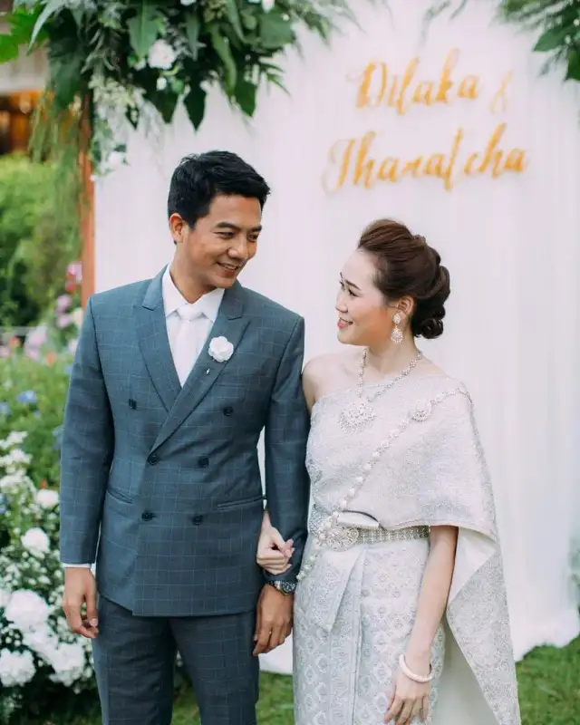 A couple in Thai wedding dress, the groom in a blue-grey double-breasted suit
