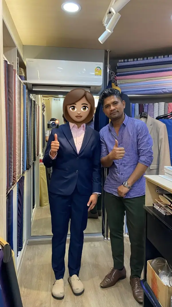 A customer in a navy trouser suit, face hidden, beside a man in a striped shirt among the cloth