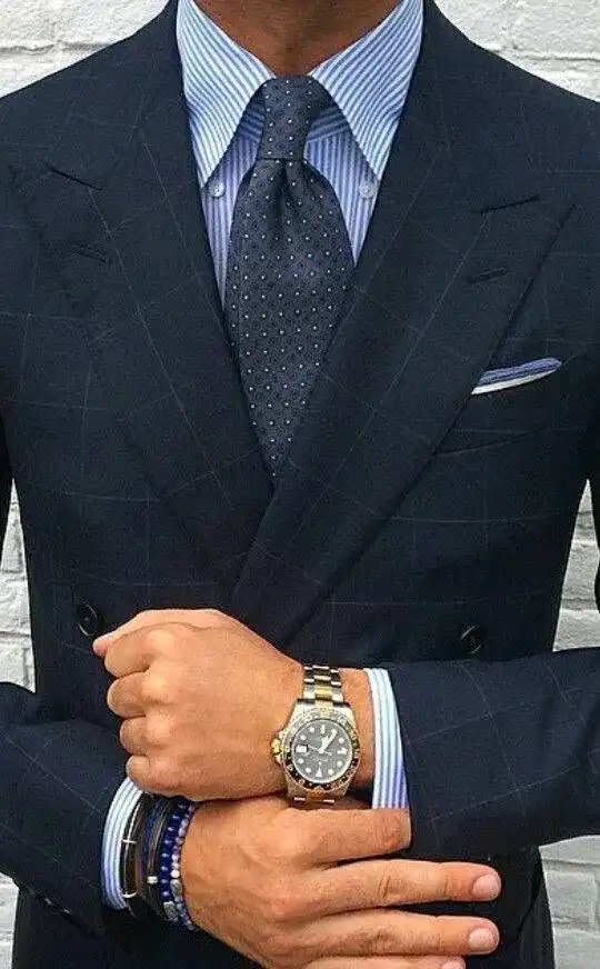 A dark double-breasted jacket over a striped shirt and tie, a watch at the wrist