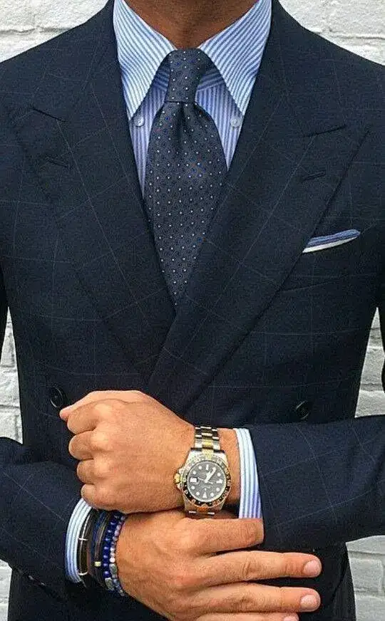 A dark double-breasted jacket over a striped shirt and tie, a watch at the wrist
