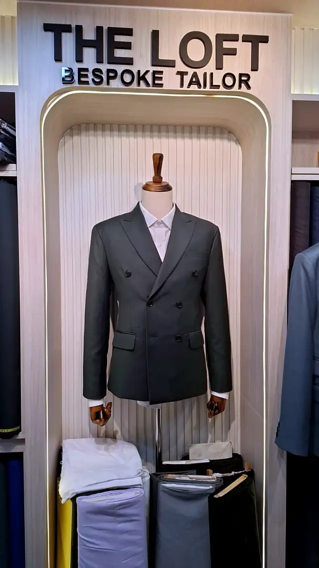 A double-breasted green jacket on a mannequin beneath a THE LOFT BESPOKE TAILOR sign