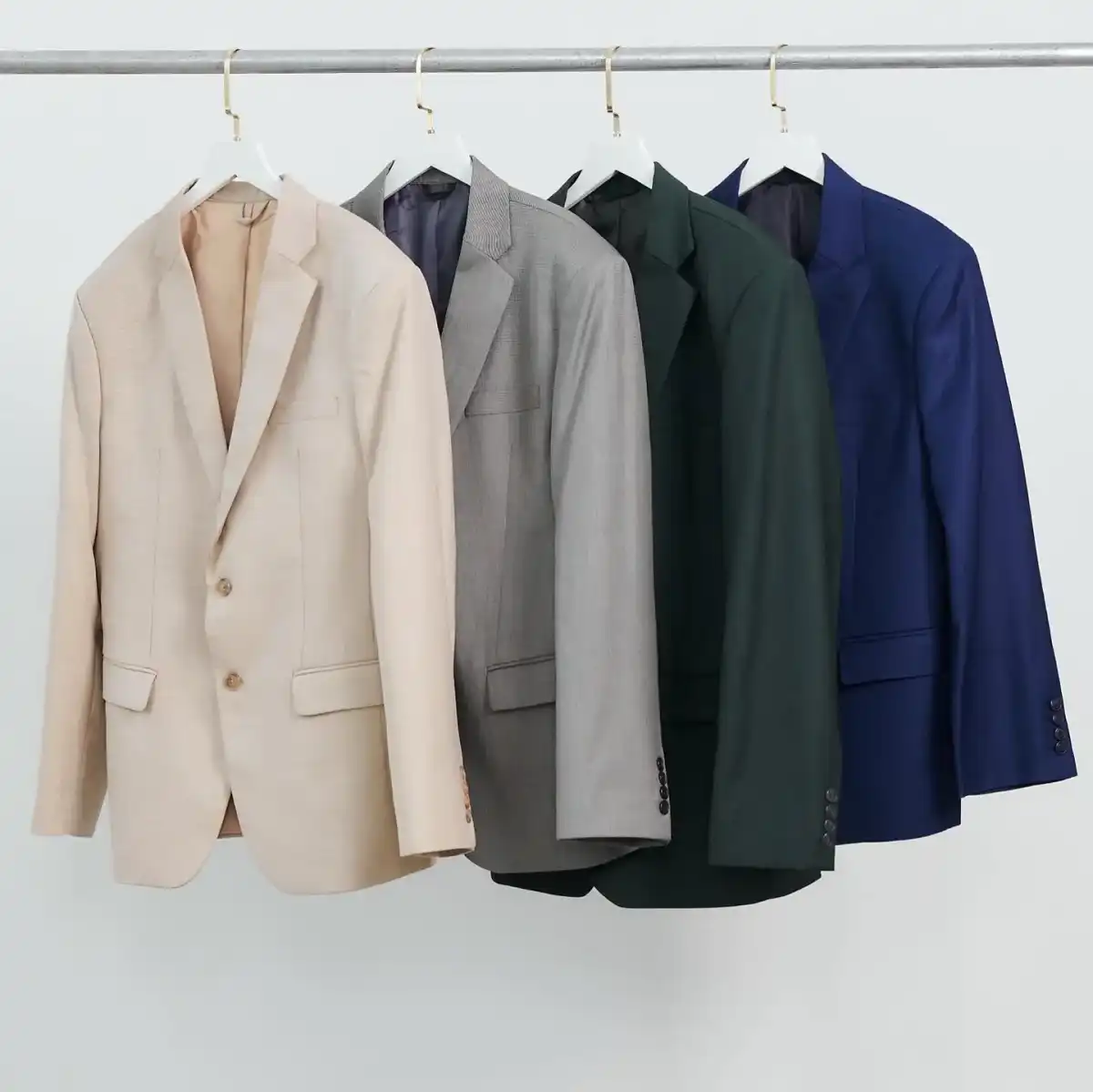 Four jackets hanging on a rail — cream, grey, dark green and navy