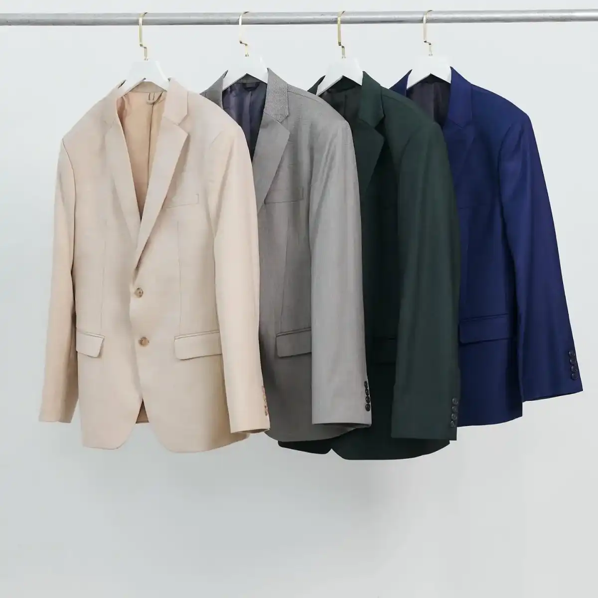 Four jackets on a rail against a white wall