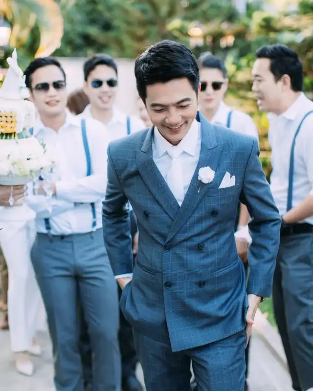 A groom in a blue suit walking with his groomsmen behind him