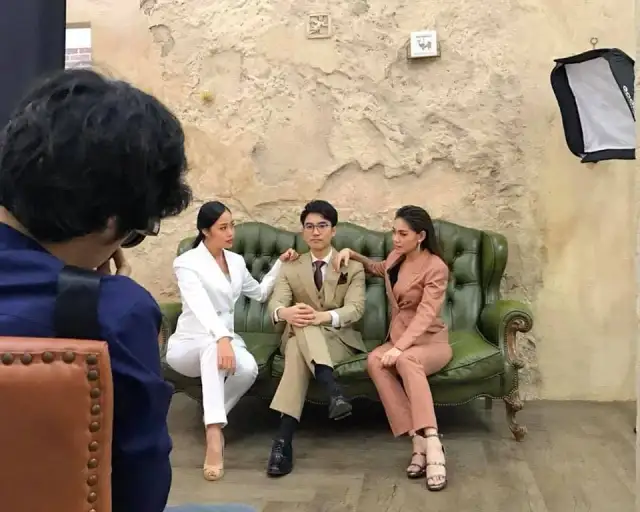 A group in tailored jackets and trousers seated on a green couch