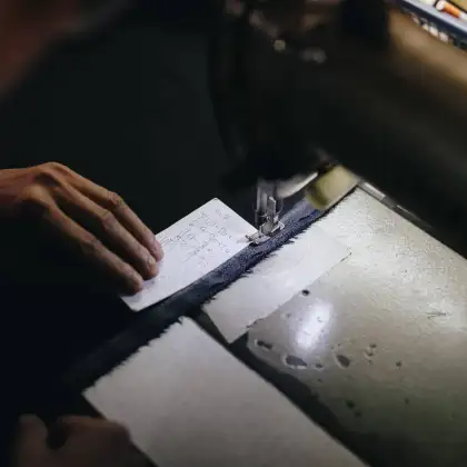 Hands marking cloth at the bench under a work lamp