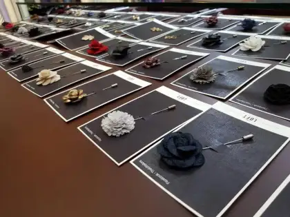 Lapel pins, bow ties and cufflinks laid out in rows on presentation cards