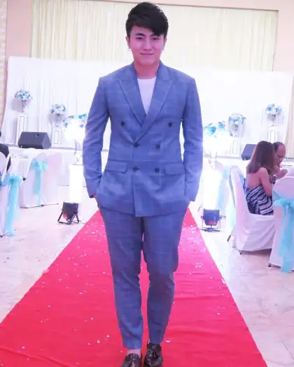 A man in a blue double-breasted suit walking a red carpet