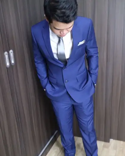 A man in a blue suit photographed from above against a panelled wall