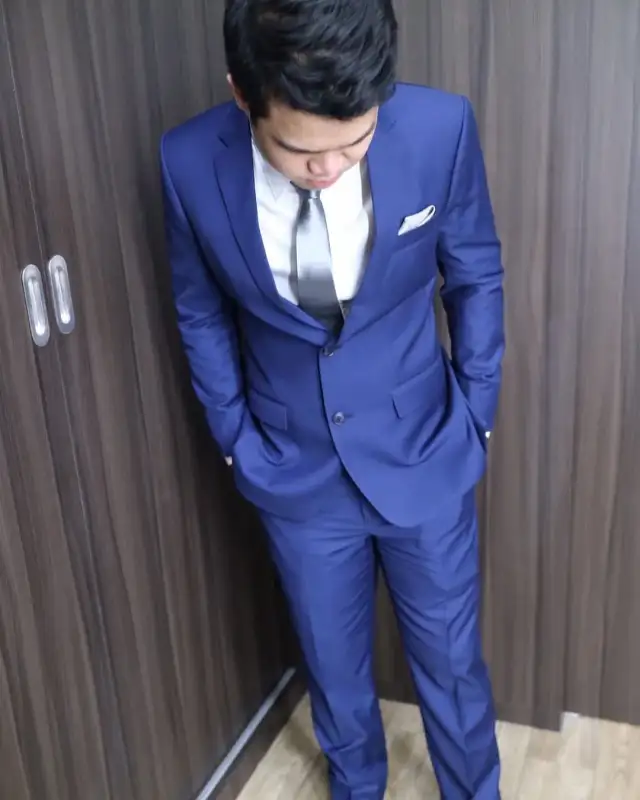 A man in a blue suit photographed from above against a panelled wall