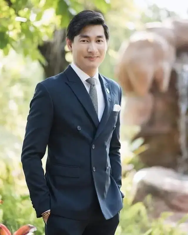 A man in a navy suit and tie standing outdoors