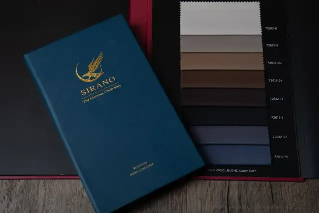 A navy cloth book open beside a card of grey and taupe swatches