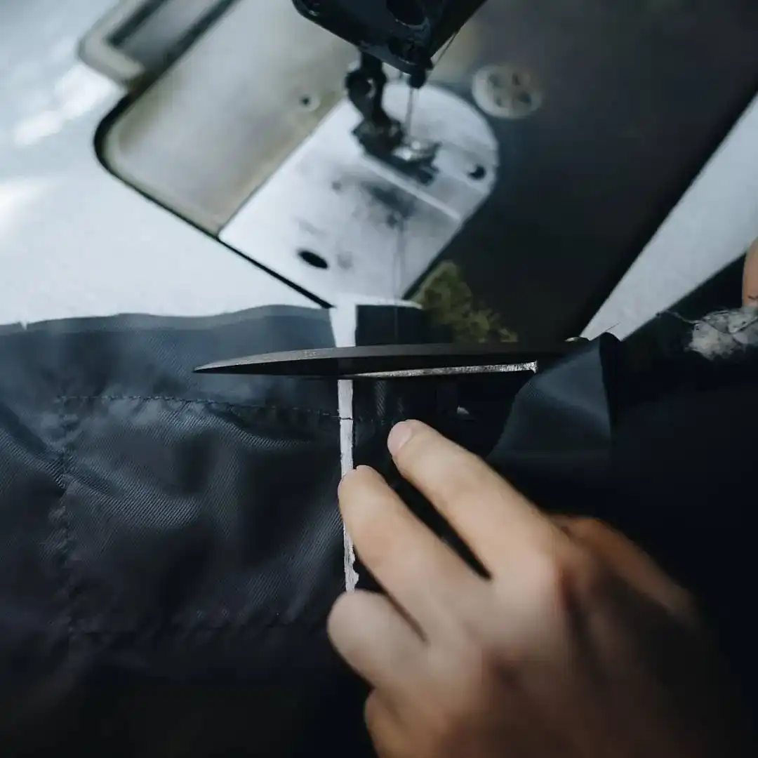 Shears cutting dark cloth beside a sewing machine