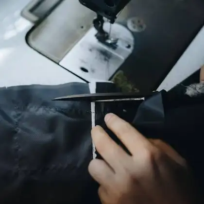 Shears cutting dark cloth beside a sewing machine