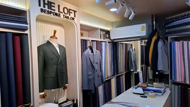 Inside the shop: rolls of cloth, jackets on a rail and the cutting table