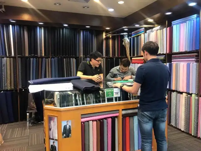 The shop interior — a wall of rolled cloth above the counter and cutting table