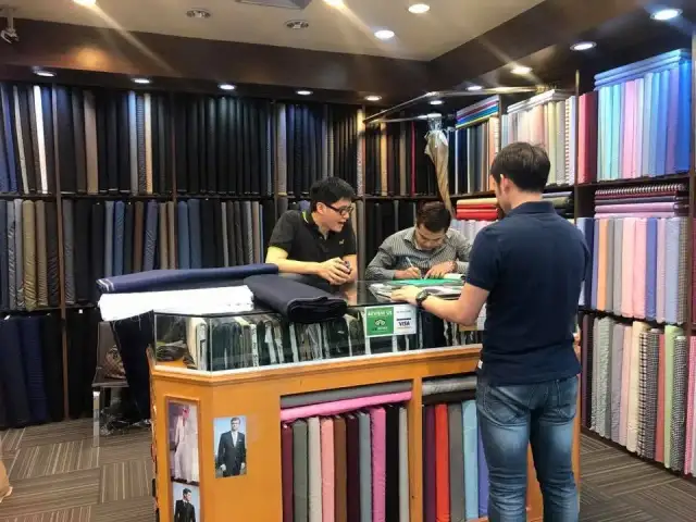 The shop interior — a wall of rolled cloth above the counter and cutting table