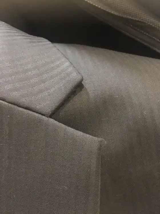 The sleevehead and shoulder seam of a taupe jacket in close view