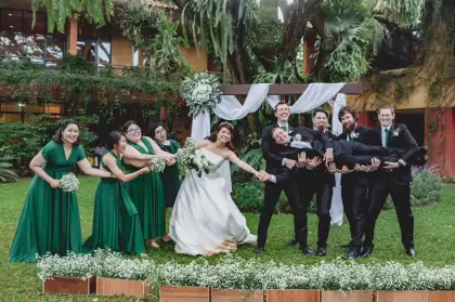A wedding party outdoors, bridesmaids in green beside the groomsmen in dark suits
