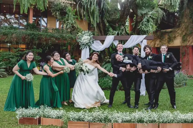 A wedding party outdoors, bridesmaids in green beside the groomsmen in dark suits