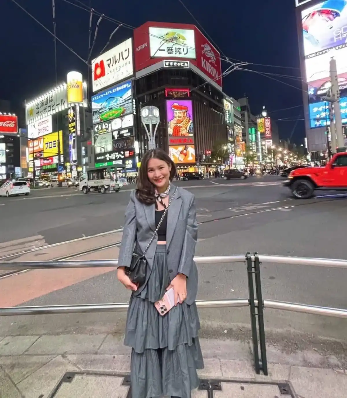 A woman in a grey layered outfit on a city street at night