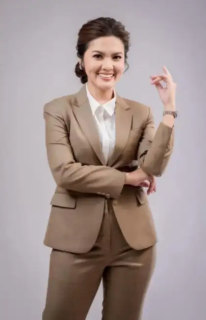 A woman in a tan suit with her arms folded