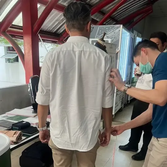 A tailor measuring a customer's back and sleeve